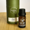 Ylang Ylang essential oil bottle beside a green Aroma Sanctuary storage canister on a wood surface; 100% essential oil with dropper cap visible.